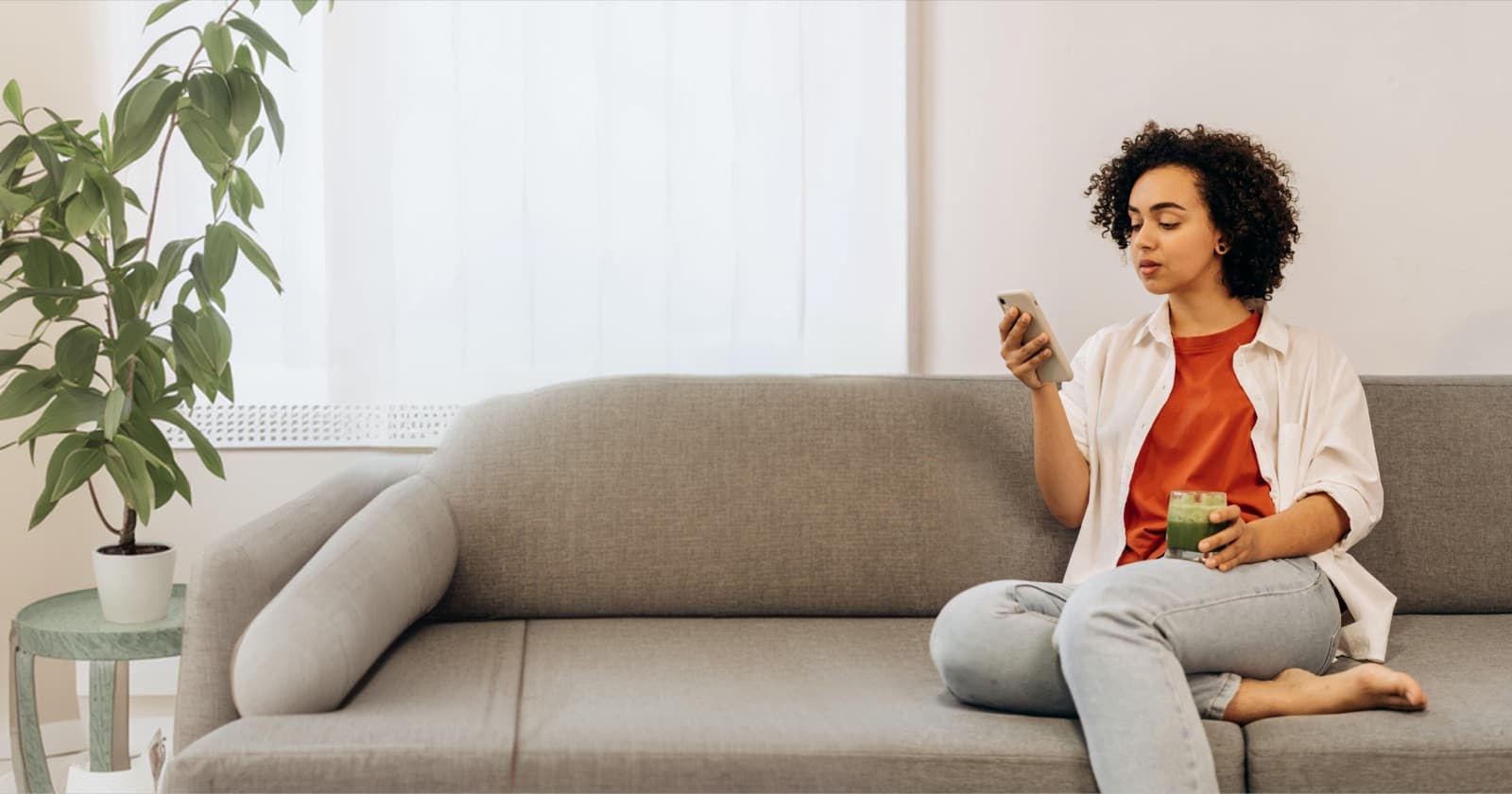A woman relaxing on a couch at home, checking her phone.